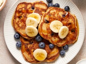 Three Dairy Free Oat Milk Pancakes on a plate topped with berries and banana.