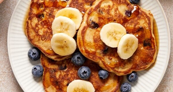 Three Dairy Free Oat Milk Pancakes on a plate topped with berries and banana.