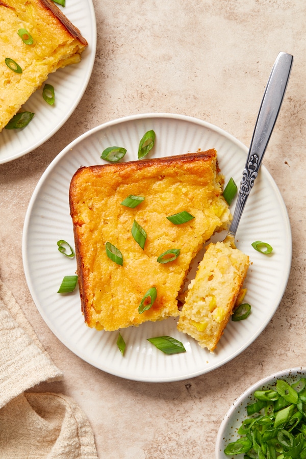 A scoop of Dairy Free Cornbread Casserole on a plate with a bite taken out.