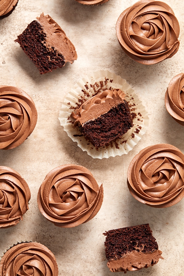 Several Lactose Free Chocolate Cupcakes on a beige surface.