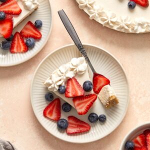 Slices of Dairy Free No Bake Cheesecake on plates topped with berries.