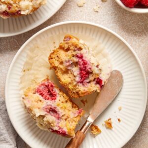 A Dairy Free Raspberry Muffin split open on a plate with a knife.