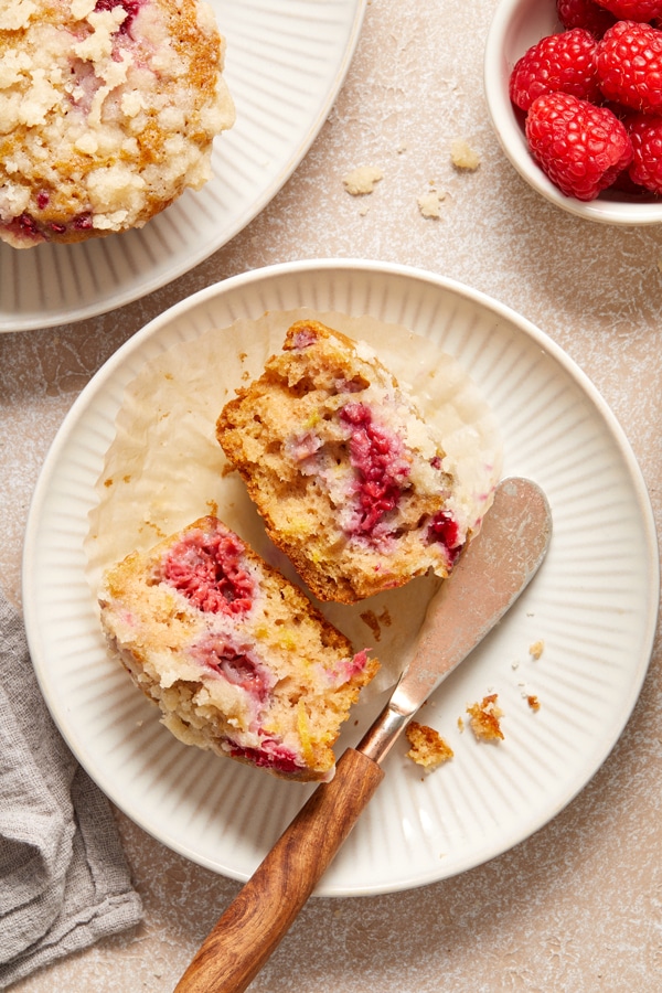 A Dairy Free Raspberry Muffin split open on a plate with a knife.