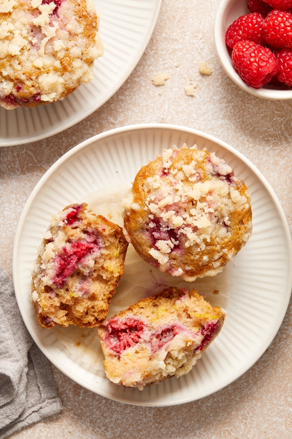 Two Dairy Free Lemon Raspberry Muffins on a plate with one split in half.