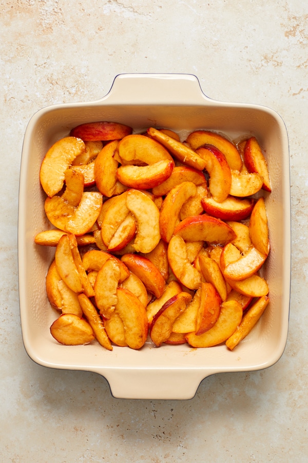 Sliced fresh peaches arranged in a baking dish.