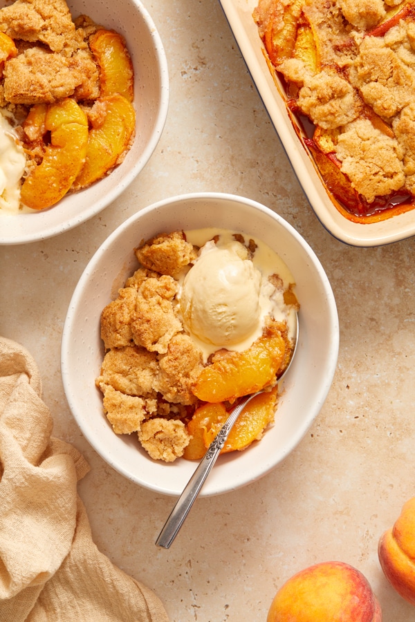 Two bowls of Dairy Free Cobbler topped with vanilla ice cream.