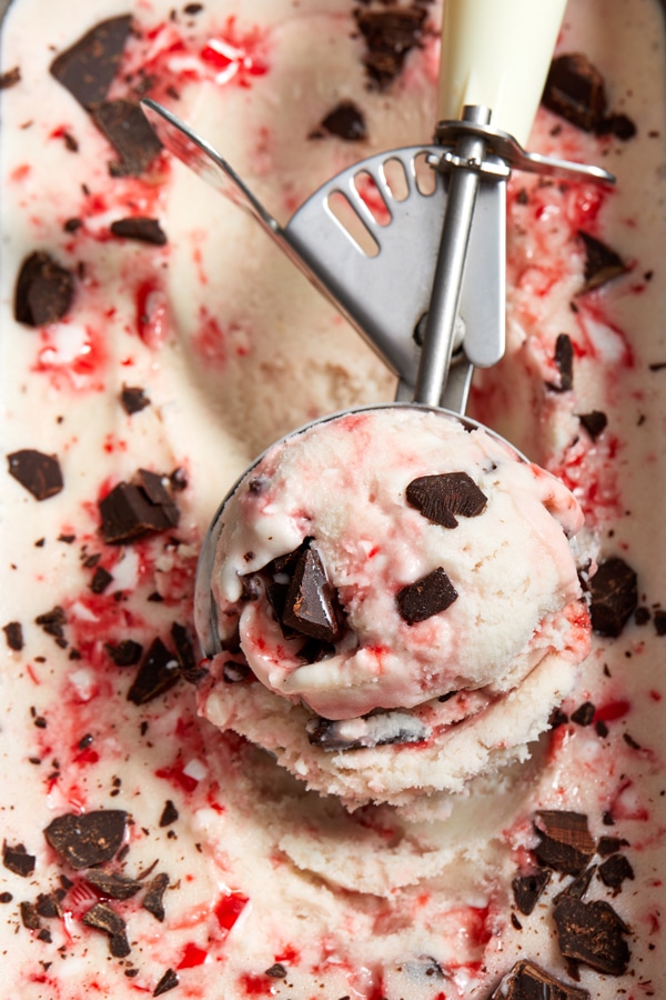 A big scoop of Dairy Free Peppermint Stick Ice Cream in an ice cream scooper.