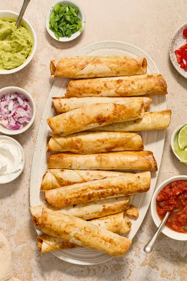 Dairy Free Chicken Taquitos on a platter with toppings to the side.