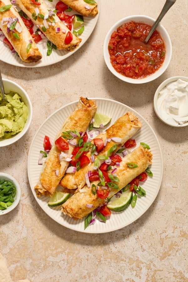 Three Dairy Free Taquitos on a plate with toppings.