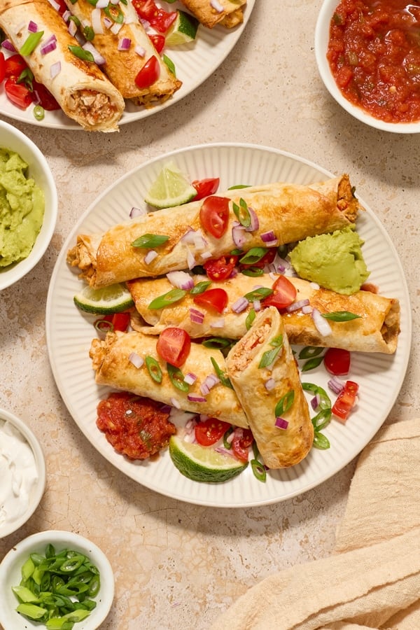 Several Dairy Free Gluten Free Taquitos on a plate with one cut open.