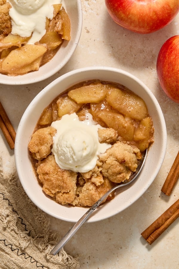 A bowl of Dairy Free Apple Cobbler with slightly melted vanilla ice cream.